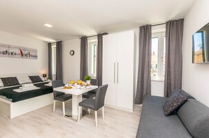 Una sala moderna con un sofá, mesa de comedor y una cama.