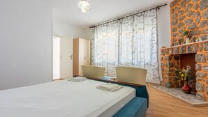 Een hotelkamer met een bed, twee stoelen, een stenen openhaard en uitzicht naar buiten.