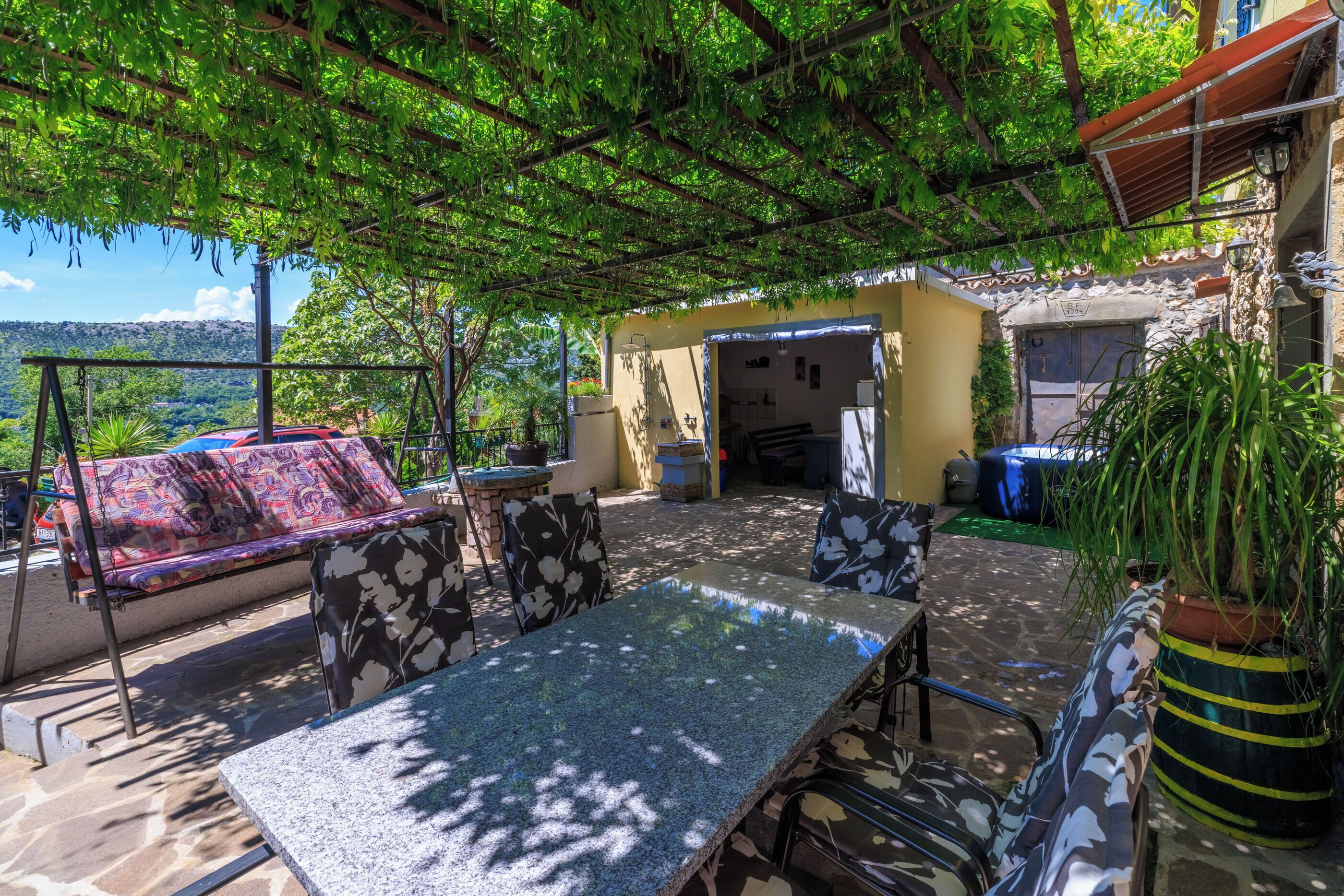 Un patio al aire libre con una mesa, sillas, una hamaca y vistas del paisaje.