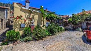 A residential area with a yellow house, a red car, and a gravel driveway. - House Sevgi (Bribir)