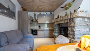A modern living room with a grey sofa, a wooden dining table with a lace tablecloth, and a bowl of fruit. - House Sevgi (Bribir)