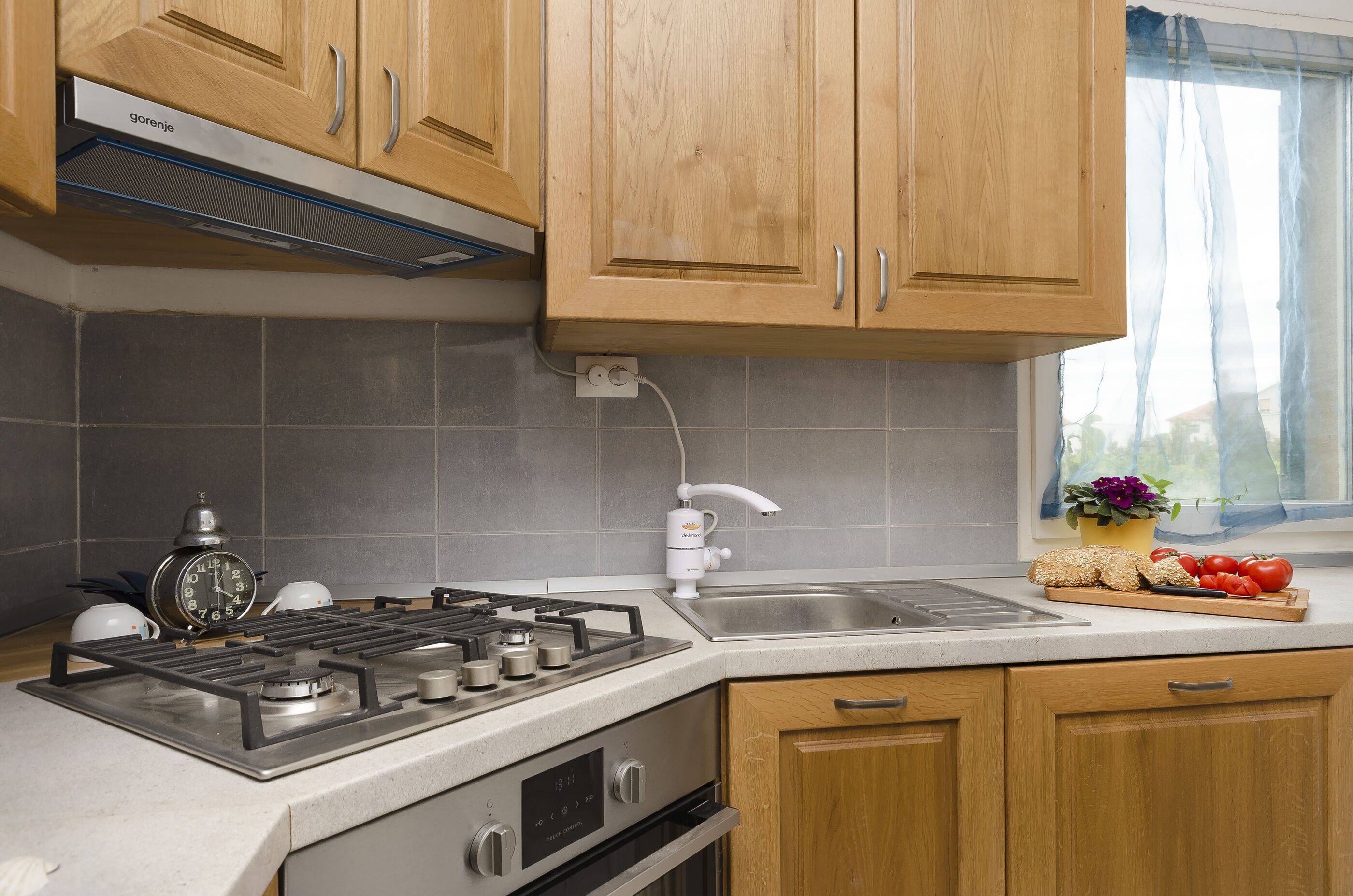 A kitchen with wooden cabinets, a gas stove, a built-in oven, a sink, and a window with a view.