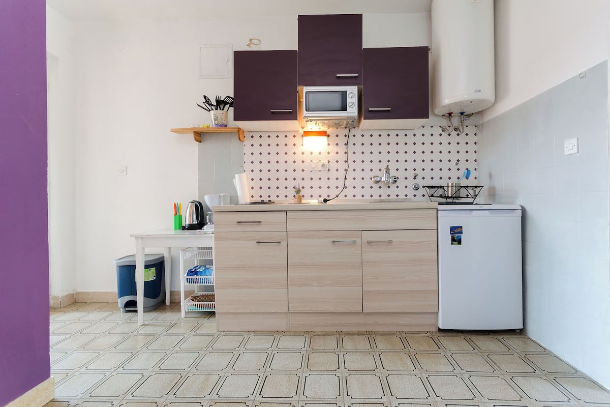 A compact kitchen with a microwave, refrigerator, and sink.