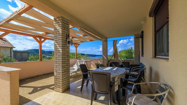 Une terrasse extérieure avec une table et des chaises, une pergola et une vue sur le paysage.