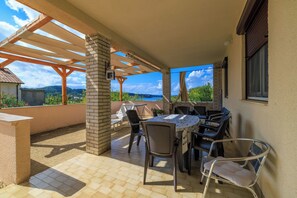 Eine Terrasse im Freien mit Tisch und Stühlen, einer Pergola und Blick auf die Landschaft.