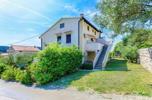 Une maison à deux étages avec un balcon, un escalier et un jardin.