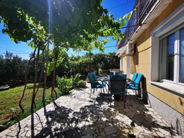 A patio with stone flooring, outdoor furniture, and a view of a garden and building.