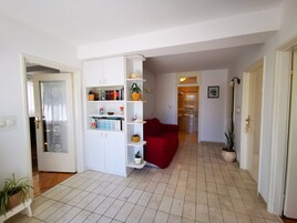 A living room with a white bookshelf, a red sofa, and a tiled floor.