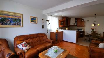 Una sala de estar con un sofá de cuero marrón, una mesa de centro de vidrio y un cuadro en la pared.