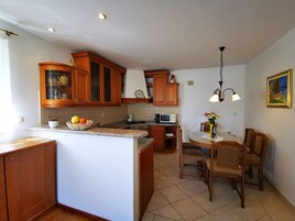 A kitchen with wooden cabinets, a dining area with a table and chairs, and a small island with a fruit bowl.