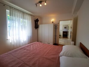 Ein Schlafzimmer mit einem großen Bett, einem Kleiderschrank, einem Wäscheständer und einem Spiegel.