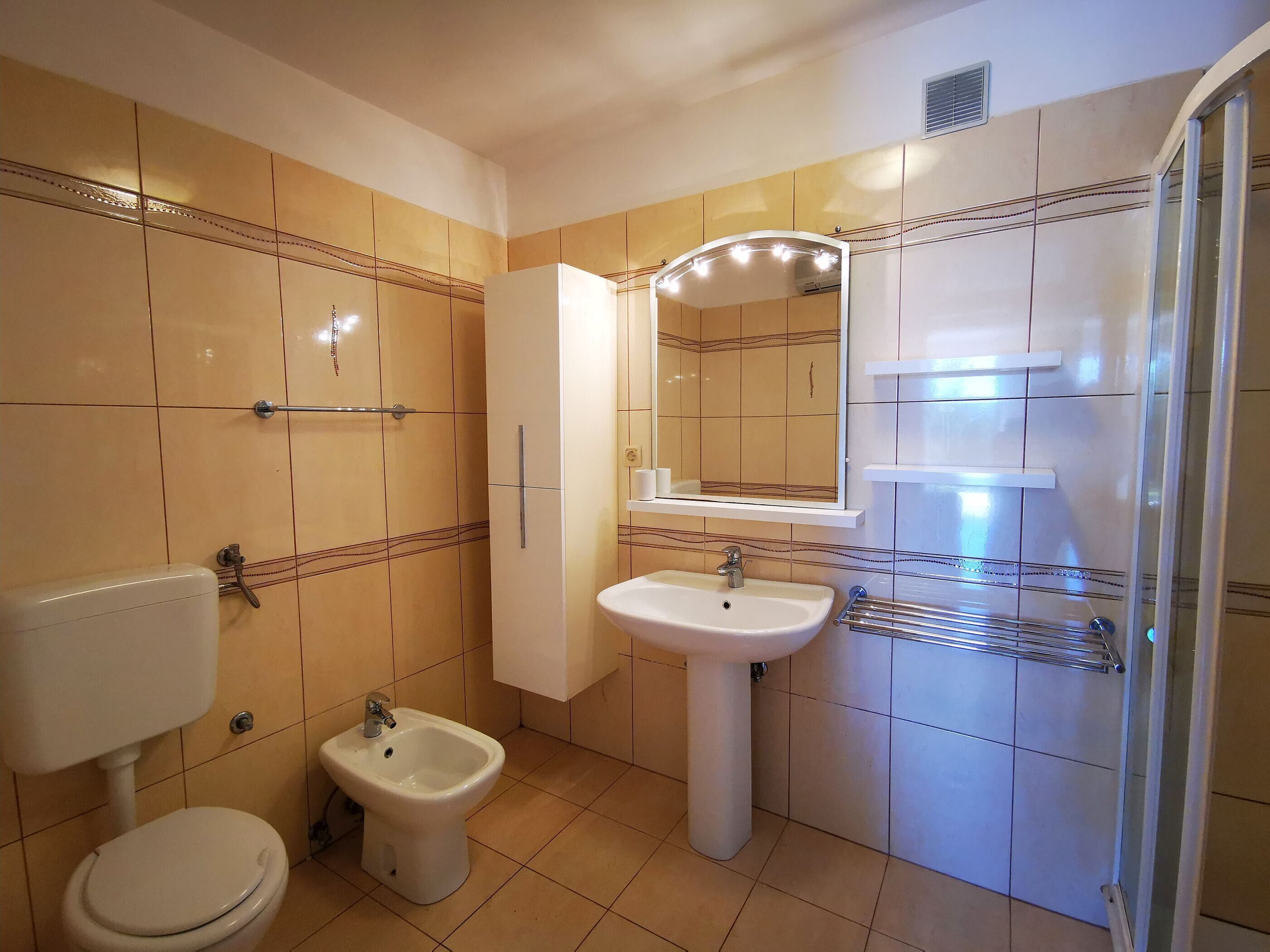 Ein Badezimmer mit Toilette, Bidet, Waschbecken und Spiegel.