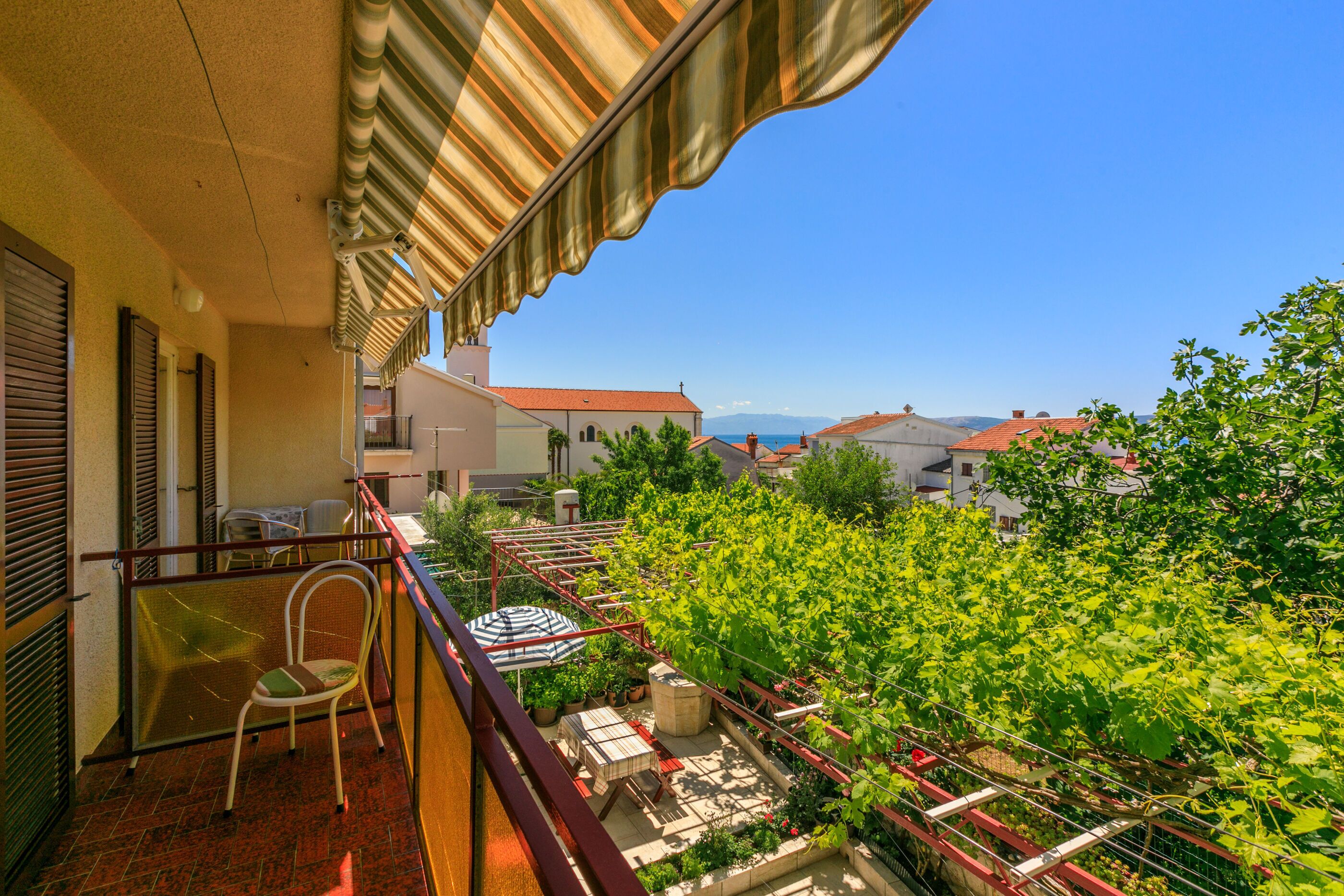 Ein Balkon mit Blick auf einen Garten und Gebäude im Hintergrund.