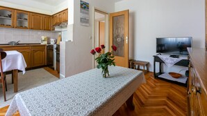 Una cocina compacta con armarios de madera, una mesa de comedor con mantel de encaje y un florero con flores rojas.