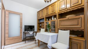 Un comedor con una mesa, sillas, armarios de madera y una televisión.