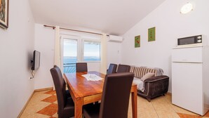 A dining area with a wooden table and chairs, a sofa, and a white refrigerator.