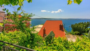 A red-roofed building with a satellite dish, surrounded by greenery and overlooking a body of water.