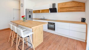 Una cocina moderna con una isla de madera, armarios blancos y un horno empotrado.