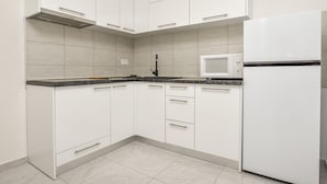 A modern kitchen with white cabinets, a built-in microwave, and a refrigerator. - Apartments Juro (Rogoznica)
