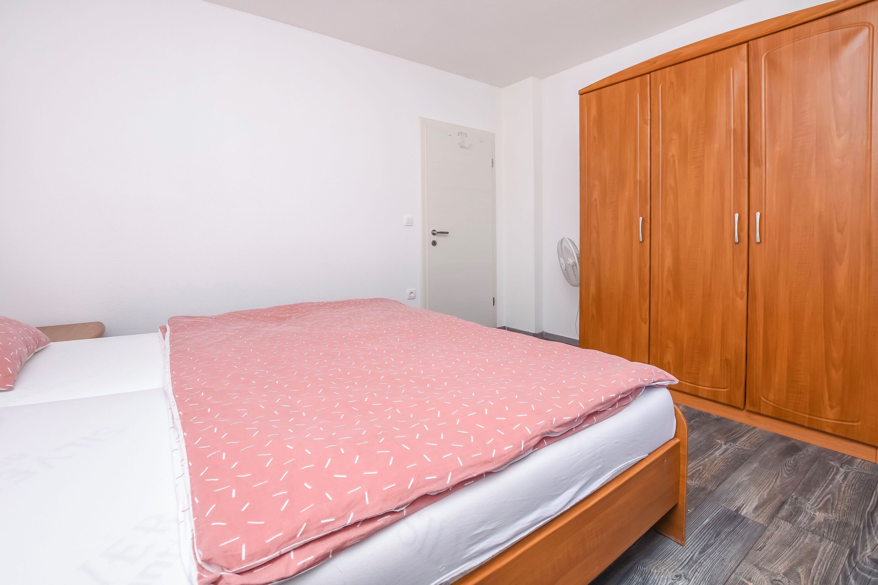 A bedroom with a bed, a wardrobe, and a door.