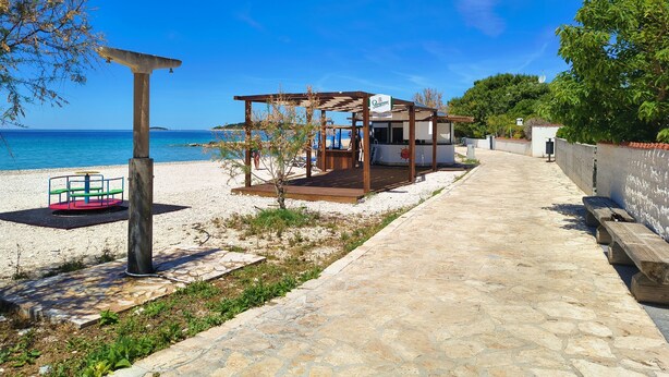 A beachside walkway leading to a wooden gazebo with a view of the sea. - Apartments Juro (Rogoznica)