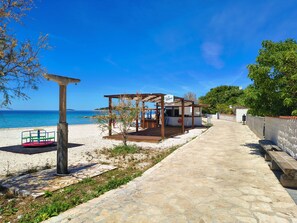 A beachside walkway leading to a wooden gazebo with a view of the sea. - Apartments Juro (Rogoznica)