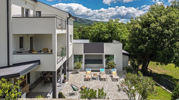Un edificio a due piani con un balcone e un patio arredato.