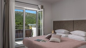 Una camera da letto con un letto, cuscini e vista su un balcone con un paesaggio panoramico.