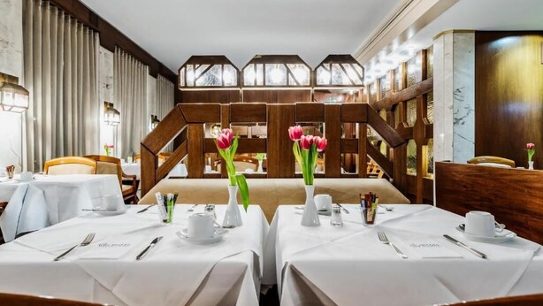 En restaurant med borde dækket til spisning, en trætrap og udsigt over det fri.