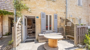 A stone building with a wooden table and benches in the courtyard.