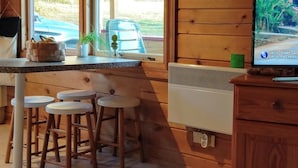 Un interior de madera con zona de cocina, que incluye una encimera, taburetes y un televisor.