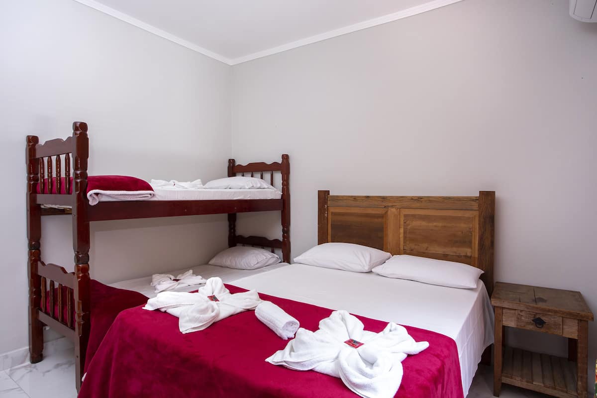 Una habitación con una cama individual, una litera y una mesita de noche.