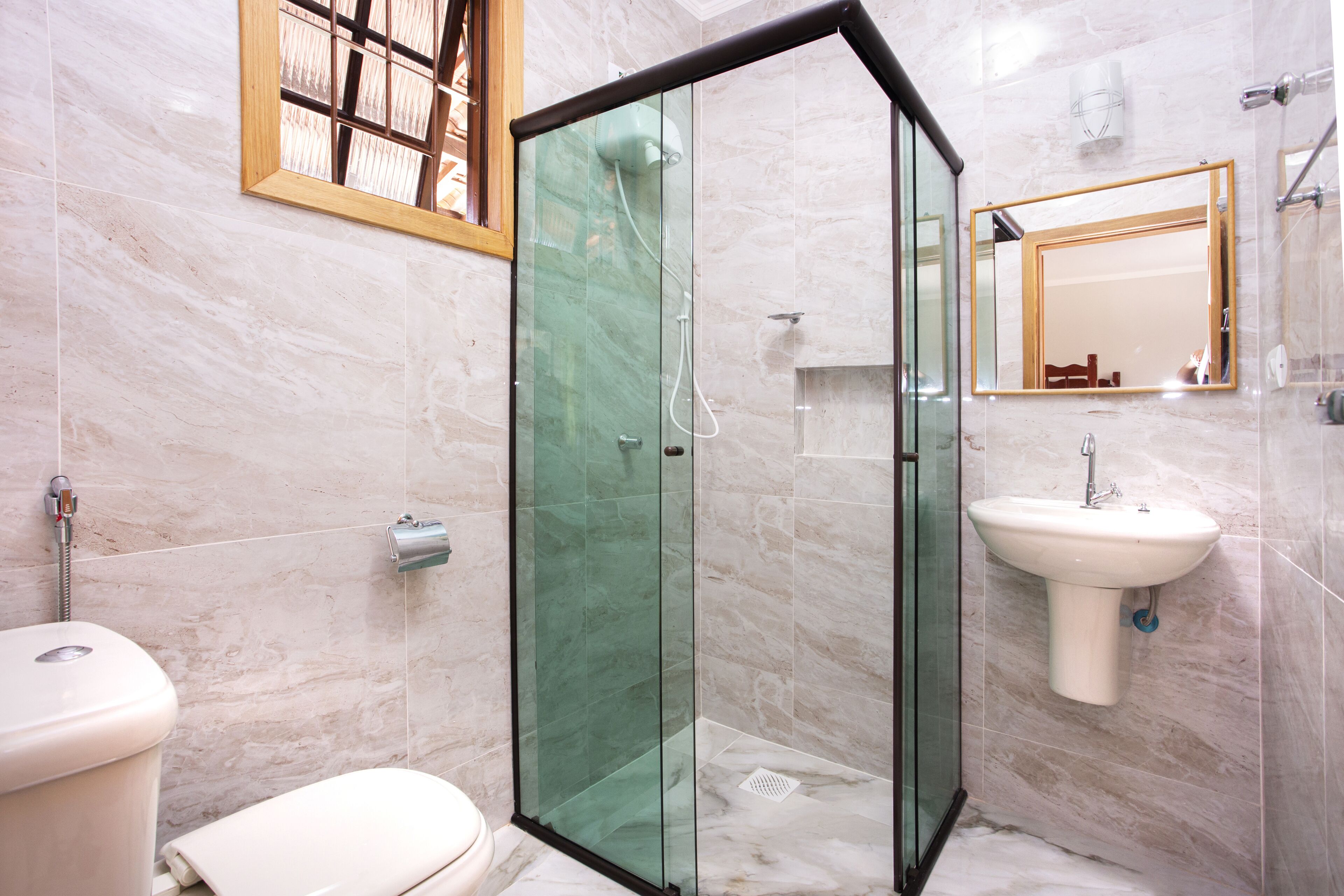 Un bagno moderno con cabina doccia in vetro, lavandino bianco e water.