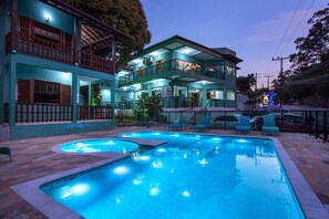 Un hotel con piscina, varios balcones e iluminación exterior.
