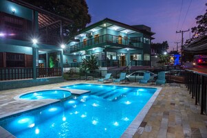 Un edificio de dos pisos con piscina, mobiliario exterior y un balcón.