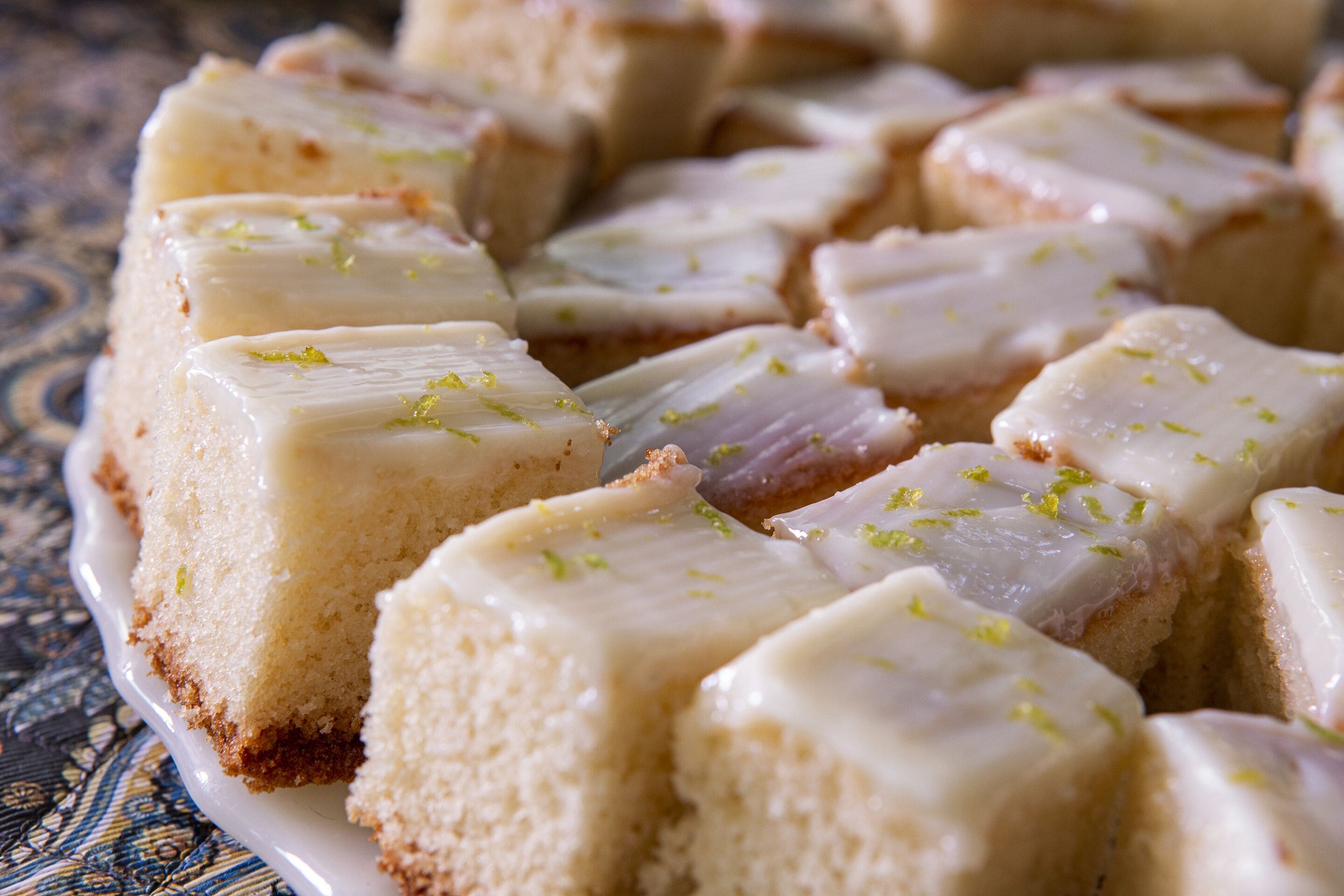 Een close-up van een taart met witte frosting en groene rasp op een bord.