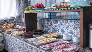 A buffet table with various food items including bread, pastries, and meats. - Pousada Guarubela Veloso (Ilhabela)