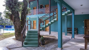 A building with a staircase leading to a balcony, a fire extinguisher, and a wooden bench. - Pousada Guarubela Veloso (Ilhabela)