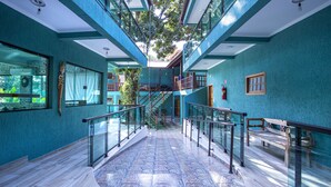 A spacious atrium with a central staircase, glass railings, and a patterned floor. - Pousada Guarubela Veloso (Ilhabela)