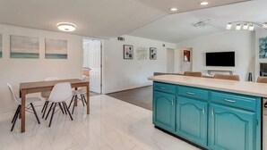 Una cocina moderna con armarios color turquesa, una mesa de comedor de madera y un televisor de pantalla plana.