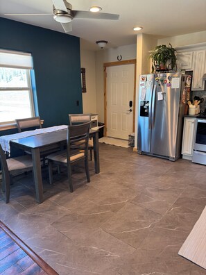 A kitchen with a dining table, chairs, a refrigerator, and a ceiling fan. - Cozy condo close to town with amazing views and trail access! (Crested Butte)