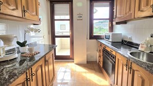 Una cocina con armarios de madera, microondas, cafetera y un lavamanos.