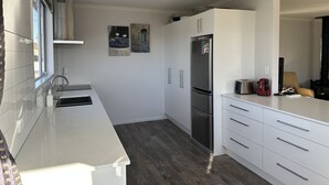 Een moderne keuken met witte kasten, een roestvrijstalen koelkast en een inbouwoven.