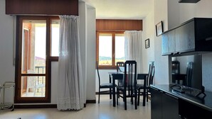 A kitchen with a dining area, a TV, and a view through the windows. - Dúplex junto a la playa de Noja - El Parque 6101 (Noja)