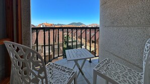 A balcony with a white table and chairs, a metal railing, and a view of buildings and mountains. - Dúplex junto a la playa de Noja - El Parque 6101 (Noja)