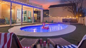 A backyard with a swimming pool, outdoor seating, and a covered patio area. - Beach+Pool+Hot Tub |  Golf Cart(incl) + Game Room (Destin)
