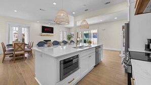 A modern kitchen with a large island, white cabinetry, and a built-in oven. - Beach+Pool+Hot Tub |  Golf Cart(incl) + Game Room (Destin)