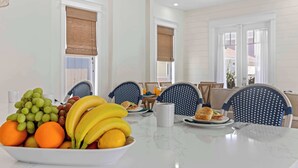 A dining area with a table set for breakfast, including fruits and a coffee mug. - Beach+Pool+Hot Tub |  Golf Cart(incl) + Game Room (Destin)