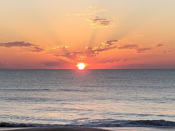 A sunset over a calm sea with a clear horizon.