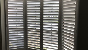 Janela de canto com persianas horizontais, permitindo entrada de luz natural no ambiente.